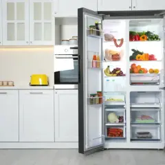 Otwarta, nowoczesna lodówka side-by-side pełna świeżych produktów. Zastanawiasz się, jaką lodówkę kupić? Ta pokazuje, jak przechowywać żywność.