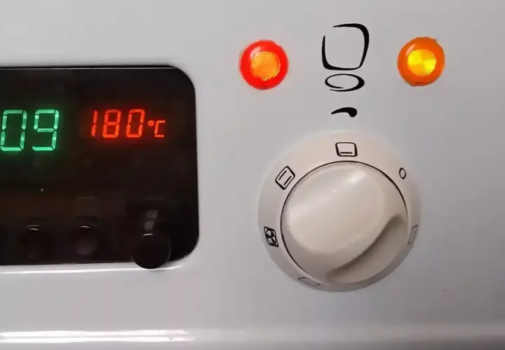 Piekarnik Mastercook: cyfrowy wyświetlacz pokazuje 180°C, a pokrętła sterują funkcjami. Czerwona lampka sygnalizuje pracę.
