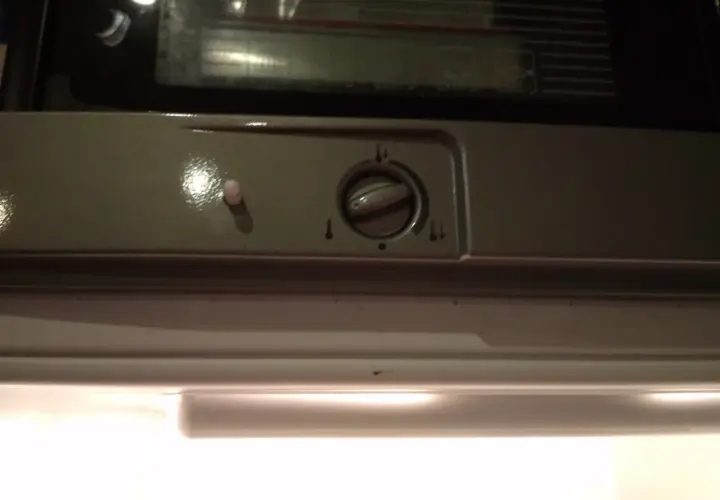 Pokrętło regulacji temperatury w lodówce Indesit z ikonami termometru.