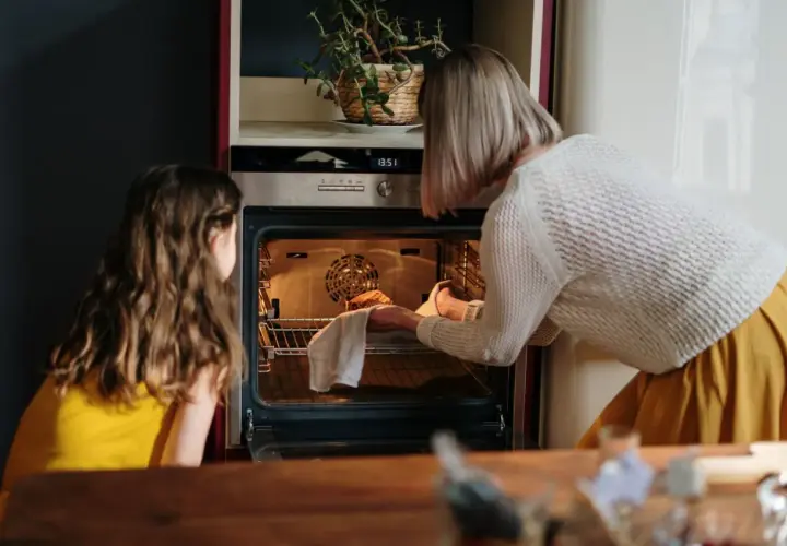 Mama i córka wkładają ciasto do rozgrzanego piekarnika. To ich pierwsze uruchomienie piekarnika po przeprowadzce.