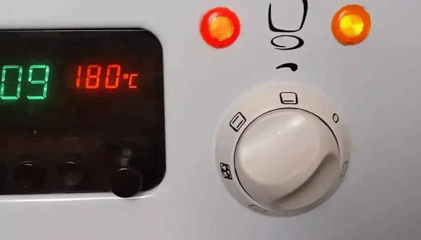 Piekarnik Mastercook: cyfrowy wyświetlacz pokazuje 180°C, a pokrętła sterują funkcjami. Czerwona lampka sygnalizuje pracę.