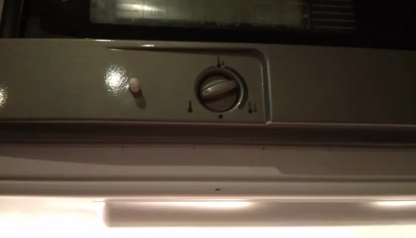 Pokrętło regulacji temperatury w lodówce Indesit z ikonami termometru.