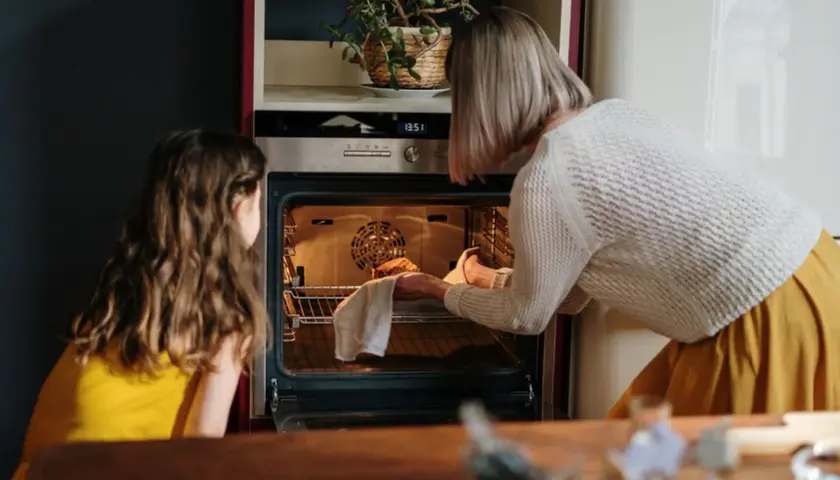 Mama i córka wkładają ciasto do rozgrzanego piekarnika. To ich pierwsze uruchomienie piekarnika po przeprowadzce.