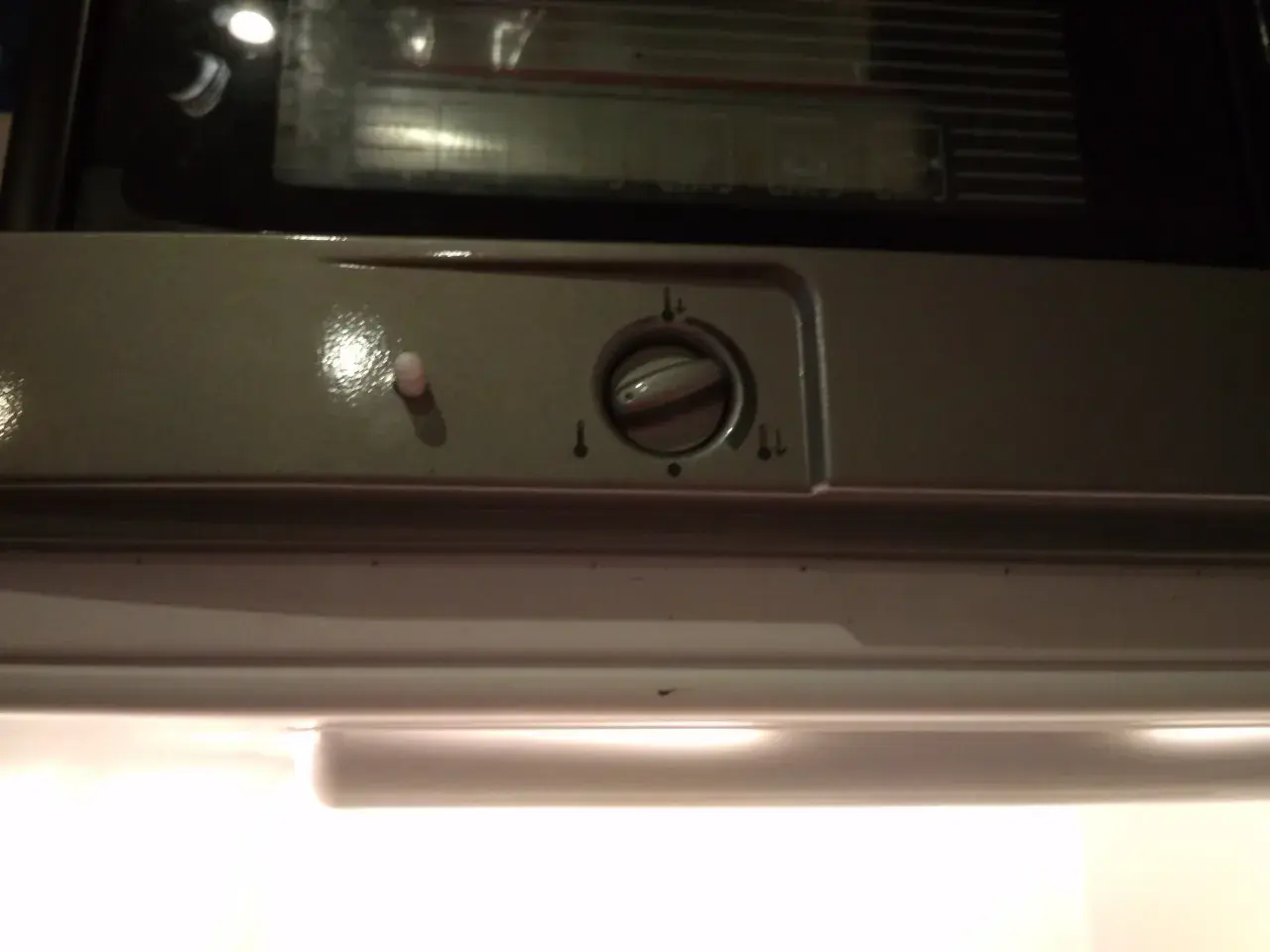 Pokrętło regulacji temperatury w lodówce Indesit z ikonami termometru.